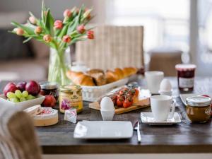 una mesa con alimentos para el desayuno y un jarrón de flores en von Witte 2, en Zingst