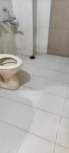 Łazienka z toaletą jest wyłożona białymi kafelkami. w obiekcie Hotel Shree w mieście Indore