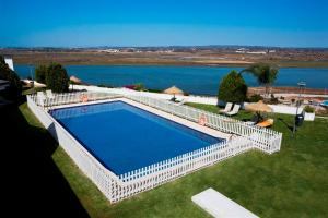 a swimming pool with a white fence next to a lake at Parador de Ayamonte in Ayamonte