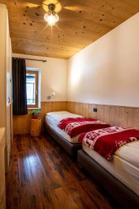 two beds in a room with wood floors and a ceiling at Appartamento Abete in Livigno