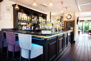 eine Bar in einem Restaurant mit Stühlen und einer Uhr in der Unterkunft Campanile Milton Keynes - Fenny Stratford in Milton Keynes