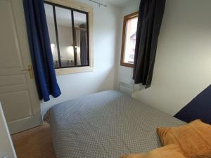 1 dormitorio con 1 cama y una ventana con cortinas azules en Snowliday - Appartement Rénové en résidence 4* pour 4 pers. Valmeinier 1900 en Valmeinier