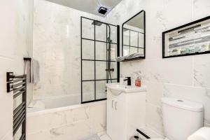 a white bathroom with a tub and a toilet and a sink at Beauty Close to Coast, Stunning interior, By Air Premier in Newhaven +14 photos