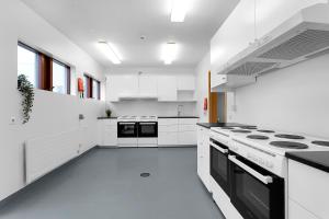 a white kitchen with white cabinets and black appliances at Víðines Guesthouse in Reykjavík