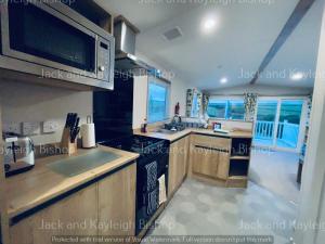 a kitchen with a stove and a microwave at 3-Bedroom Holiday Home with Valley Views in Newquay