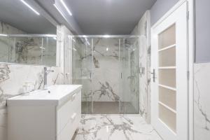 a white bathroom with a shower and a sink at Luxurious apartment in Kolonaki in Athens