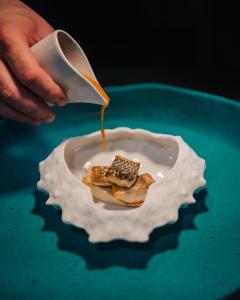 a person pouring syrup onto a plate of food at Porto Covo Praia Hotel & SPA in Porto Covo