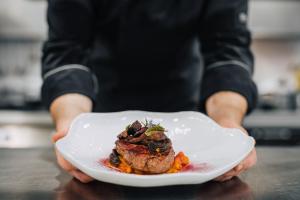 a person holding a plate of food on a table at Porto Covo Praia Hotel & SPA in Porto Covo