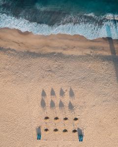a group of seven umbrellas in the sand on a beach at Porto Covo Praia Hotel & SPA in Porto Covo