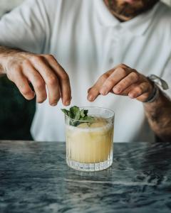 a man putting a mint leaf into a drink at Porto Covo Praia Hotel & SPA in Porto Covo