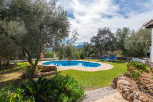 a backyard with a swimming pool and trees and grass at El Chorro Villas Casa Rosaleda in El Chorro