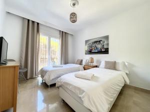 una camera con due letti e una tv di Renovated 2 bedroom Apt 5 min walk to beach RDR279 a Estepona
