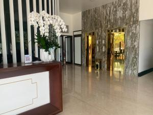 un vestíbulo con un jarrón con flores blancas. en Lotus Hotel & Apartment, en Hai Phong