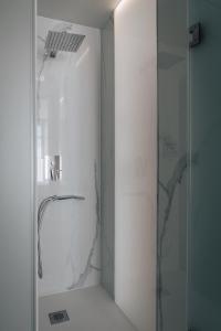 a bathroom with a shower with a glass door at Porto Covo Praia Hotel & SPA in Porto Covo