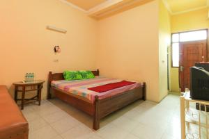 Dormitorio pequeño con cama y TV en Penginapan Pondok Rizqi, en Surabaya