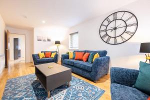 sala de estar con 2 sofás azules y reloj en Modern City Centre Apartment in Inverness, en Inverness