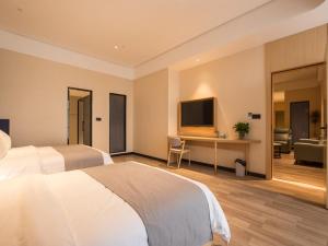 a bedroom with a bed and a desk with a television at LanOu Hotel Heyuan Dongyuan Jianji University in Heyuan