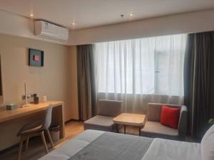 a hotel room with a bed and two chairs and a desk at LanOu Hotel Tianshui Bus Terminal Station in Tianshui