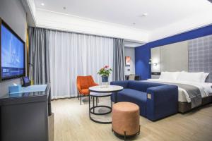 um quarto de hotel com uma cama e um sofá azul em LanOu Hotel Jingzhou East Gate of Ancient City Wanda Plaza em Jingzhou