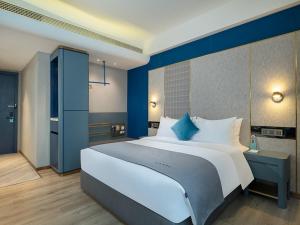 um quarto com uma cama grande e paredes azuis em LanOu Hotel Shaoguan University em Shaoguan