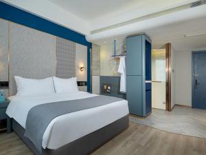 um quarto com uma cama grande e uma parede azul em LanOu Hotel Shaoguan University em Shaoguan
