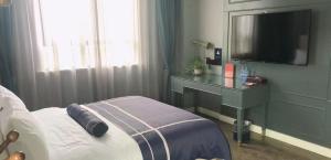 um quarto com uma cama e uma secretária com uma televisão em LanOu Hotel Liangshan Leibo Leishui Lake em Leibo