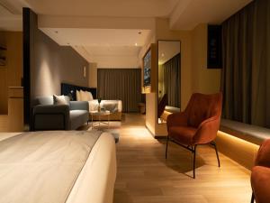 a hotel room with a bed and a living room at LanOu Hotel Longkou Boshang Shopping Plaza in Longkou
