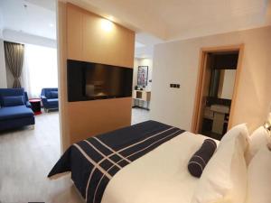 um quarto de hotel com uma cama grande e uma televisão em LanOu Hotel Yucheng Yingbin Avenue em Yuncheng