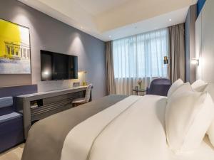 a hotel room with a large bed and a television at LanOu Hotel Qingcheng Municipal Government Shunying Plaza in Qingyuan