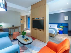 a hotel room with a bed and a flat screen tv at LanOu Hotel Yangquan North Railway Station in Yu