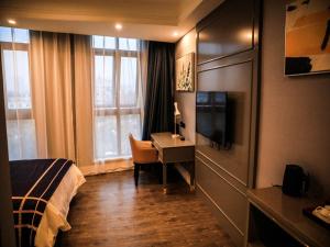 um quarto de hotel com um quarto com uma secretária e uma cama em LanOu Hotel Suzhou Yongqiao Yingbin Avenue em Suzhou