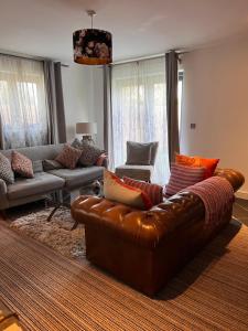 a living room with a brown leather couch and chairs at The Annex at Meadow Farm in Cambridge