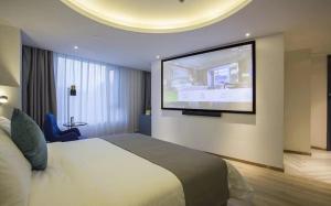 a hotel room with a bed and a flat screen tv at LanOu Hotel Zhenjiang Runzhou District Railway Station in Zhenjiang