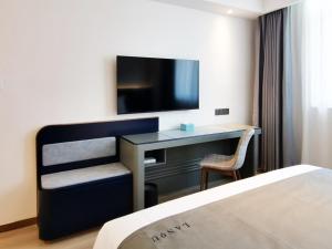 een hotelkamer met een bureau, een tv en een bed bij LanOu Hotel Taocheng Hengshui Middle School in Hengshui