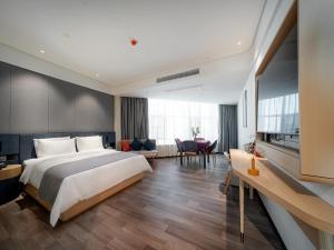 a bedroom with a large bed and a living room at LanOu Hotel Nanyang Wancheng Guangwu Emperor City in Nanyang