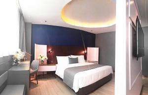 a bedroom with a bed and a desk with a bed sidx sidx sidx at LanOu Hotel Bazhou Korla Jindu Plaza in Korla