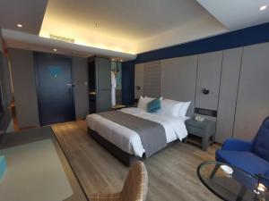 1 dormitorio con 1 cama grande y 1 silla azul en LanOu Hotel Shijiazhuang Luquan Zoo Scenic Spot, en Luquan