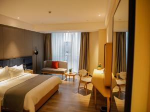 a hotel room with a bed and a living room at LanOu Hotel Jinzhou Red Star Macalline in Jinzhou
