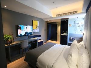 een slaapkamer met een bed, een bureau en een televisie bij LanOu Hotel Lianyungang Donghai Crystal City in Donghai
