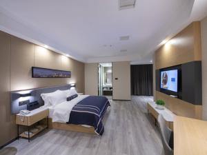 um quarto de hotel com uma cama e uma televisão de ecrã plano em LanOu Hotel Yucheng Yingbin Avenue em Yuncheng