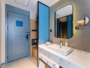 bagno con lavandino bianco e specchio di LanOu Hotel Hohhot New Town Moore City a Hohhot