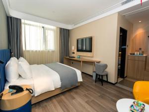 Pokój hotelowy z łóżkiem i biurkiem w obiekcie LanOu Hotel Huai'an Jinhu Suning Plaza West Health Road w mieście Jinhu