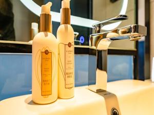 two bottles of soap sitting next to a sink at LanOu Hotel Longkou Boshang Shopping Plaza in Longkou