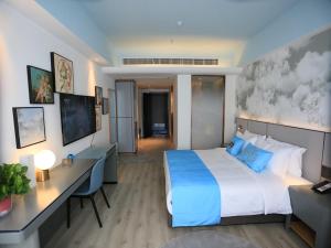 DonghaiにあるLanOu Hotel Lianyungang Donghai Crystal Cityの大きなベッドとデスクが備わるホテルルームです。