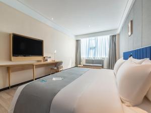 Habitación de hotel con cama grande y TV de pantalla plana. en LanOu Hotel Wanshan Tongren South Expressway Toll Station, en Tongren