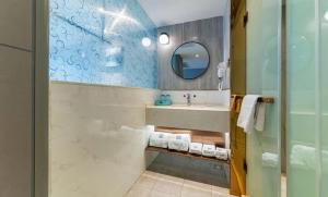 een badkamer met een wastafel en een spiegel bij LanOu Hotel Yancheng Dafeng Yongtai Plaza in Dafeng