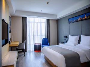 LanOu Hotel Golmud Middle Bayi Road في Golmud: غرفة الفندق بسرير كبير ومكتب