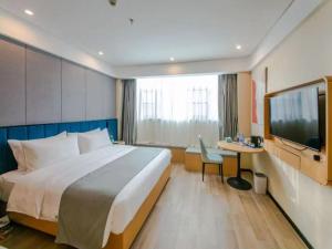 Habitación de hotel con cama grande y TV en LanOu Hotel Linyi Railway Station National Fitness Center, en Linyi