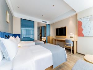 LanOu Hotel Hohhot New Town Moore City في هوهوت: غرفة نوم مع سرير أبيض كبير ومكتب