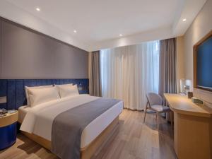 HuangdaoにあるLanOu Hotel Qingdao Golden Beach Scenic Areaの大きなベッドとデスクが備わるホテルルームです。